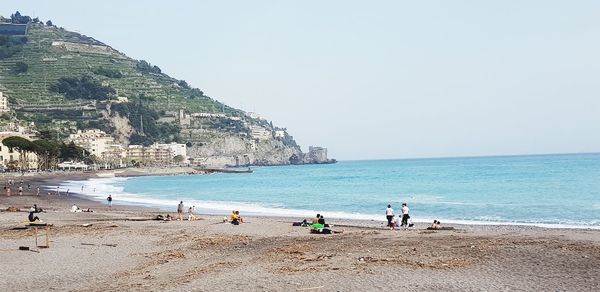 People on beach against clear sky