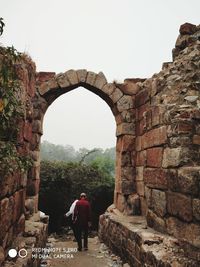 Rear view of man looking at arch against clear sky