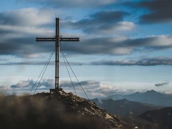 Low angle view of cross on mountain against sky