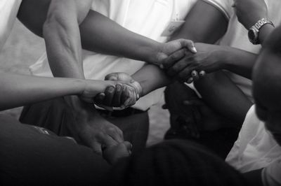 Friends holding hands while sitting in room