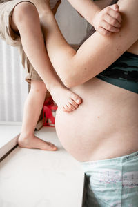 Midsection of woman holding son standing at kitchen