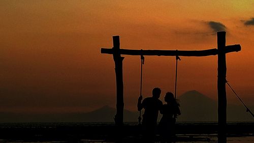 Silhouette of people in sea at sunset