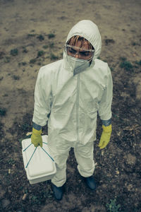 High angle view of man wearing protective suit holding basket standing outdoors