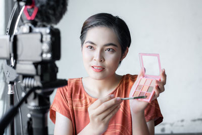 Portrait of smiling woman holding camera