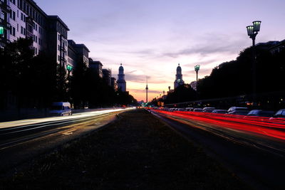 Light trails on road in city at sunset