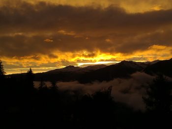 Scenic view of silhouette mountains against dramatic sky