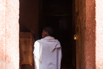 Rear view of man standing against door of building