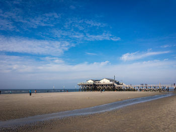 Scenic view of beach by sea against blue sky