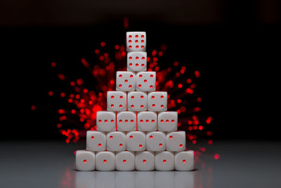 Close-up of stacked dices on table against black background
