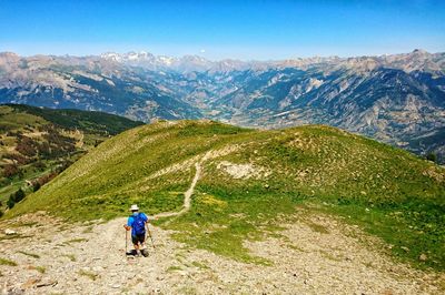 Rear view of hiker hiking on landscape