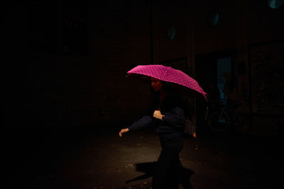 Rear view of woman with umbrella walking on street