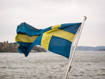 Swedish flag on pole against sea