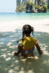 Rear view of woman sitting on beach