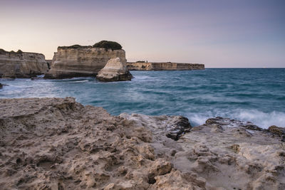 Rock formations amidst sea at salento against clear sky