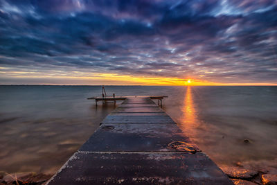 Pier over ijsselmeer against cloudy sky during sunset