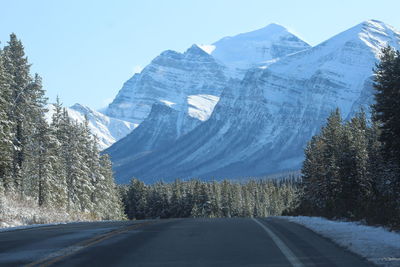 Road amidst snowcapped mountains against sky