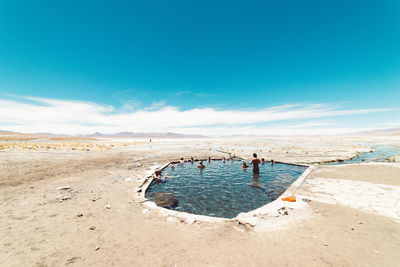 People in lake against blue sky