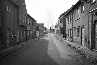 Empty road amidst buildings against sky