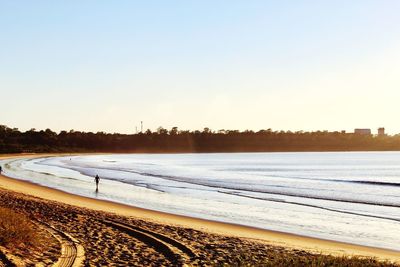 Scenic view of beach against clear sky during sunset