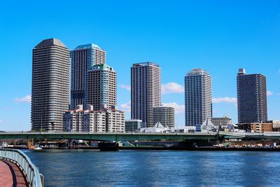Sumida riverbank in tokyo with bridge and sunny skyscrapers under blue sky