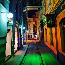 Empty alley amidst buildings in city at night