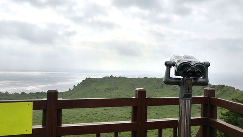 Coin-operated binoculars at observation point against sky