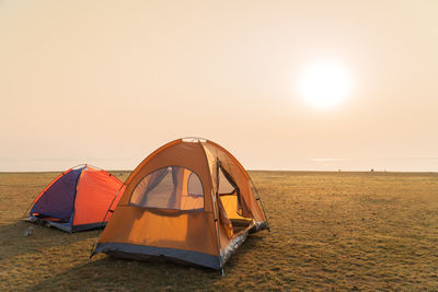 Tent on beach against sky during sunset