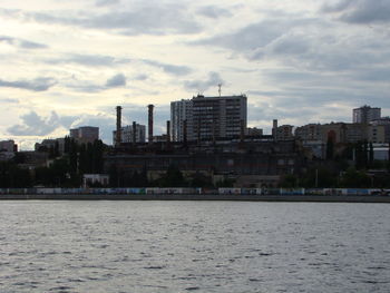 Sea by buildings against sky in city
