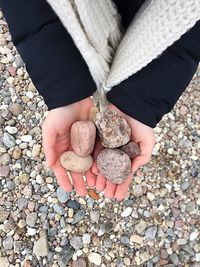 Midsection of woman holding pebbles at beach