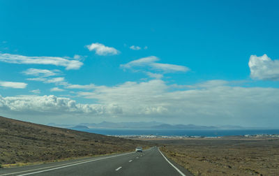 Road leading towards mountains against sky