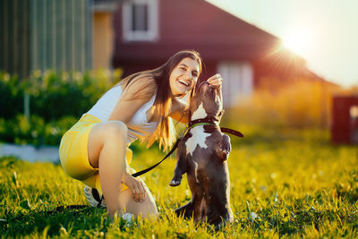 Portrait of young woman with dog on grassy field