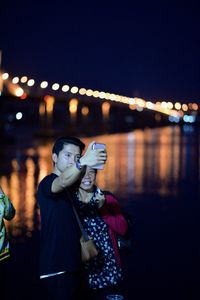 Full length of young woman with illuminated light at night