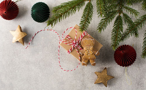 Presents and gingerbread man lie on grey background with christmas tree branches