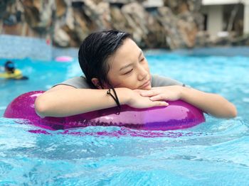 Close-up of teenage girl with inflatable ring swimming in pool