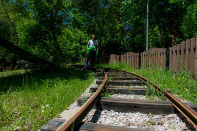 Portrait of man standing on railroad track against trees