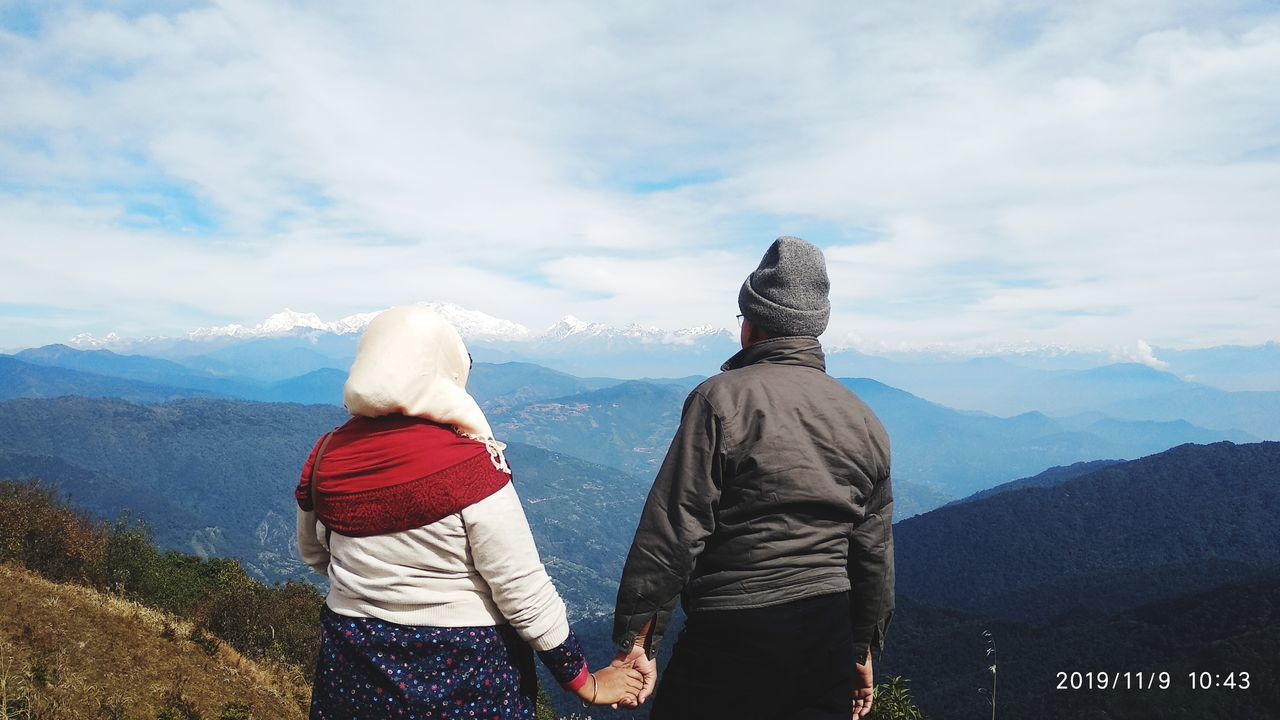 sky, cloud - sky, mountain, rear view, real people, women, two people, lifestyles, leisure activity, mountain range, beauty in nature, scenics - nature, adult, winter, clothing, togetherness, warm clothing, day, men, nature, looking at view, outdoors, hood - clothing