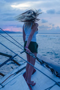 Woman standing in boat on sea against sky