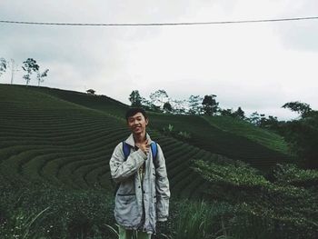 Portrait of young man standing against sky