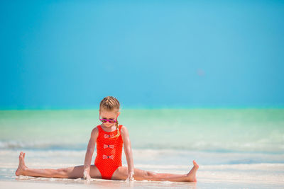 Rear view of boy sitting on beach against sky