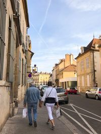 Rear view of people walking on street amidst buildings