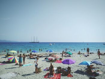 People on beach against clear blue sky