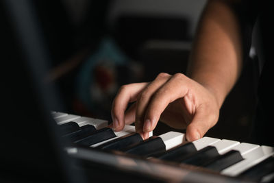 Cropped hands of woman playing piano