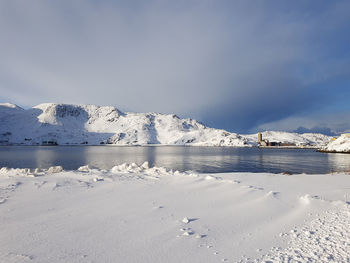 Frozen sea by snowcapped mountain against sky