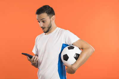 Side view of man holding soccer ball against yellow background