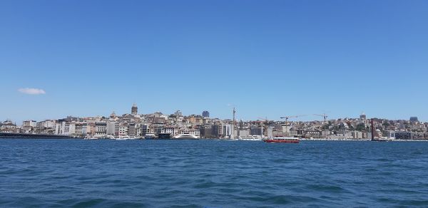 Sea by buildings against clear blue sky