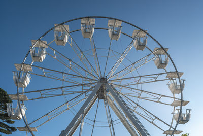 Low angle view of ferris wheel against clear blue sky