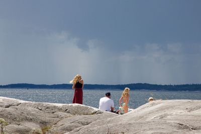 Rear view of family on rocks by sea