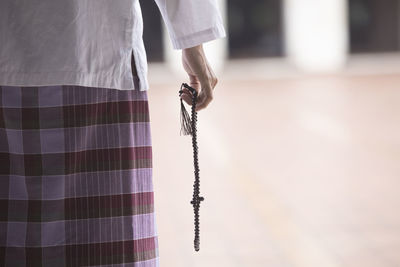 Midsection of woman holding rosary