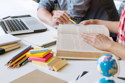 Midsection of man reading book on table