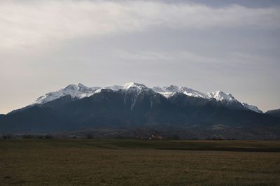 Scenic view of mountains in front of landscape against cloudy sky